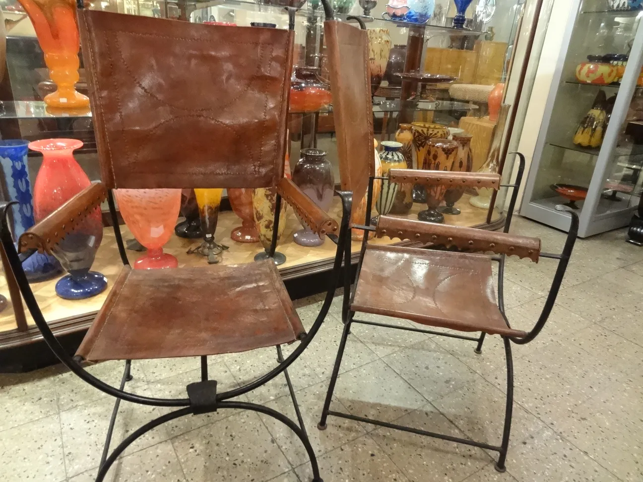 deux fauteuils anciens en cuir dans un environnement coloré avec des jarres