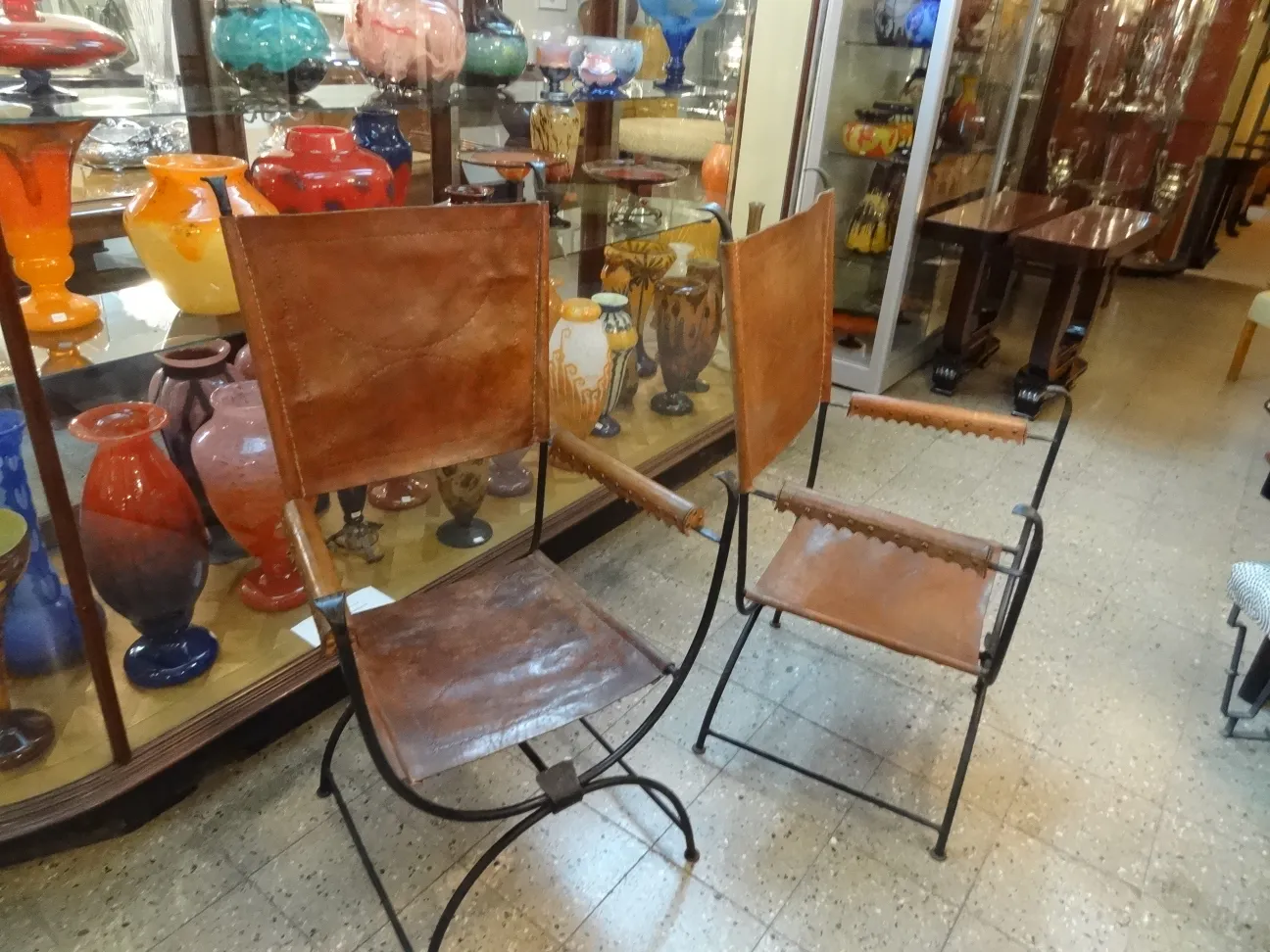 Coppia di poltrone antiche in una galleria piena di vasi colorati