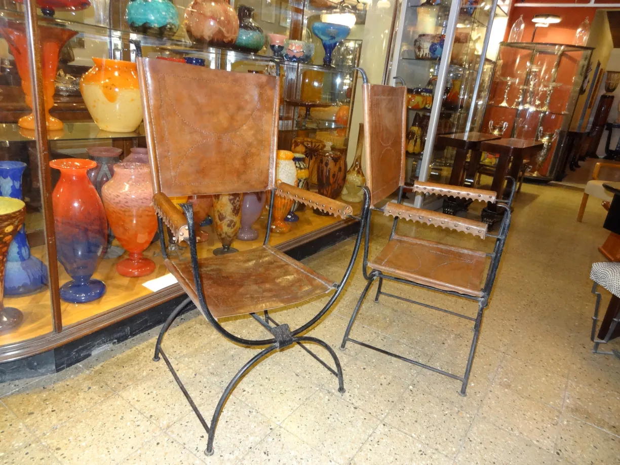 Deux fauteuils anciens dans le showroom, entourés de décorations en verre colorées.