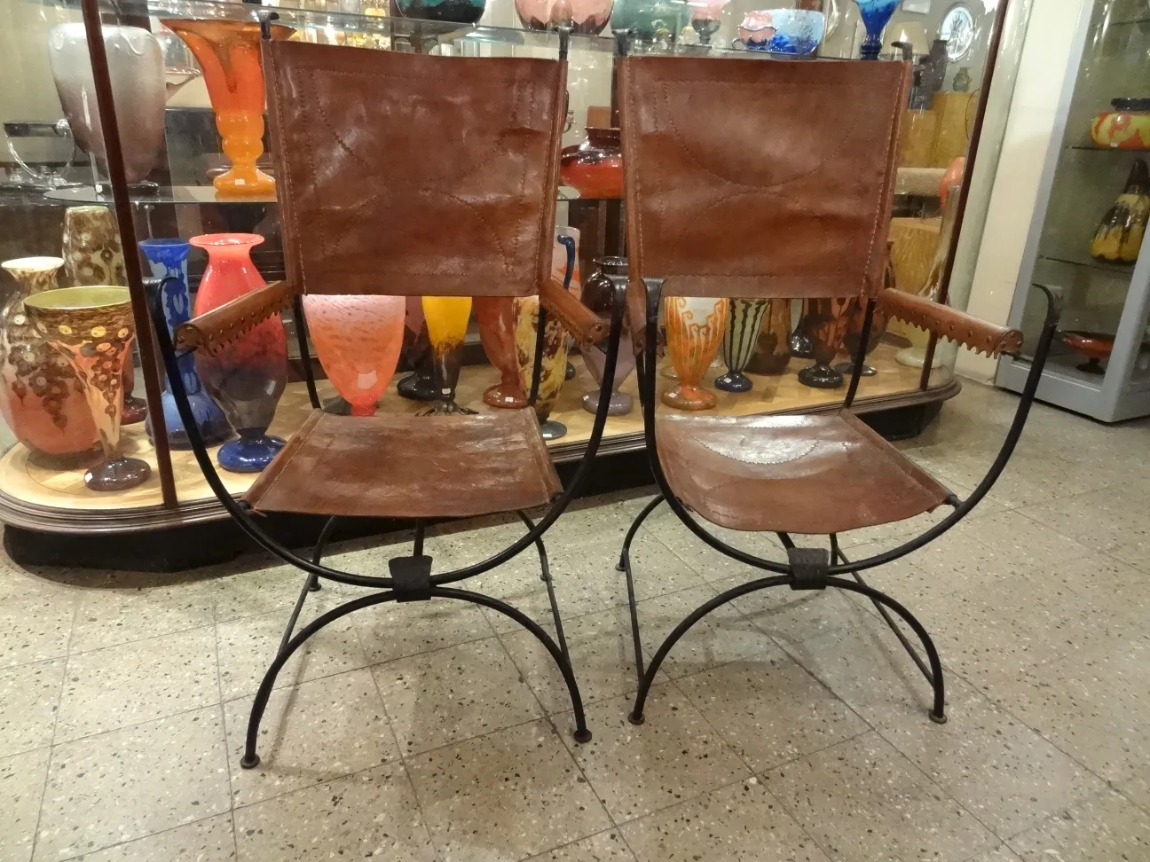 deux fauteuils antiques avec accoudoirs dans un environnement décoratif.