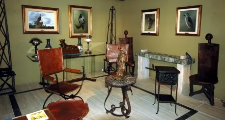 deux fauteuils anciens au design classique dans un espace décoratif avec des tableaux et d'autres meubles