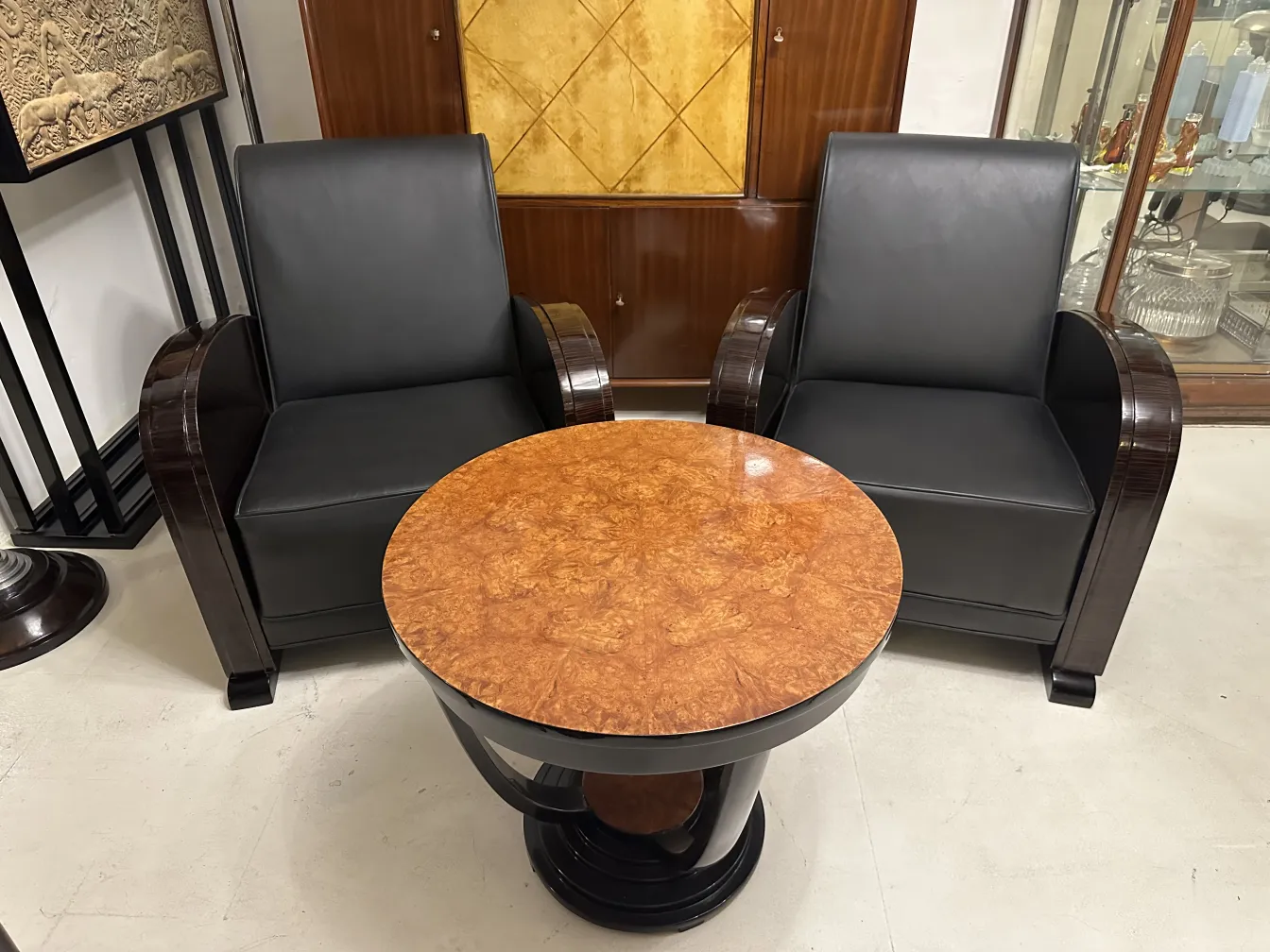 Par de sillones antiguos con tapizado negro y mesa circular