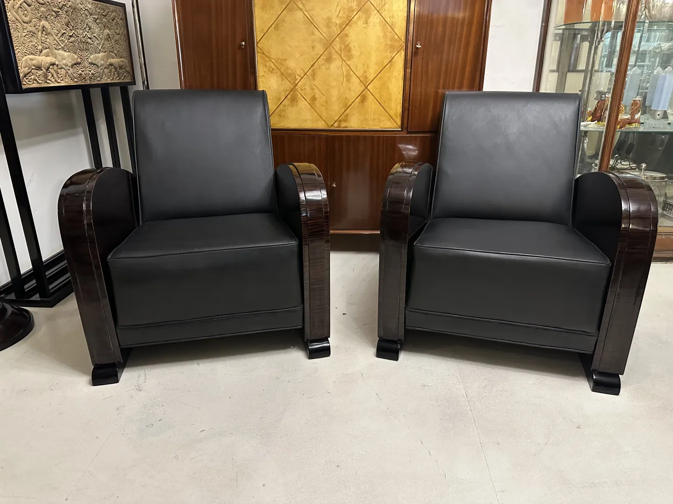 Vista de dos sillones antiguos, con tonos oscuros y diseño elegante en un entorno clásico.