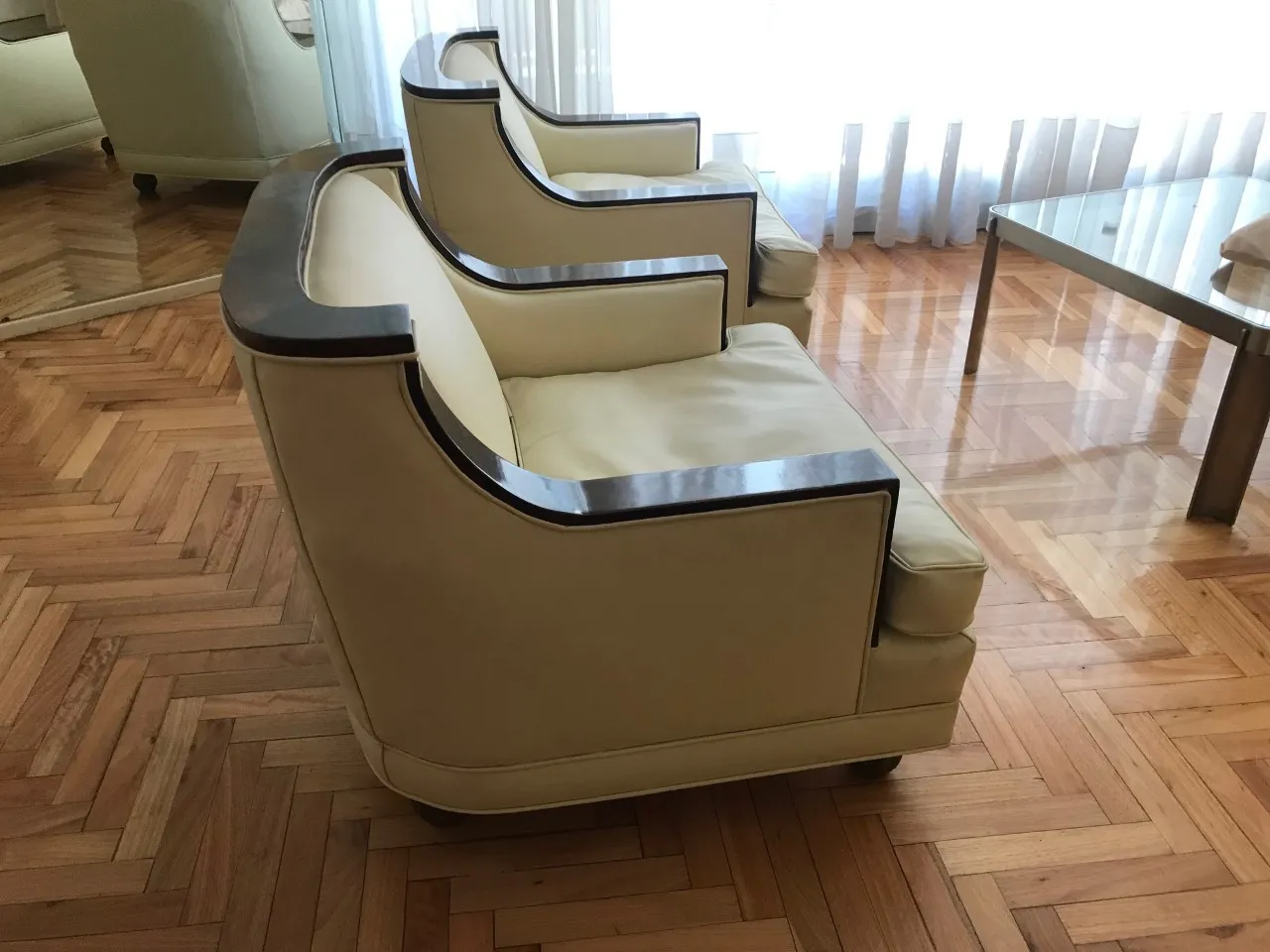 Side view of 2 vintage armchairs in a bright room with hardwood floor.