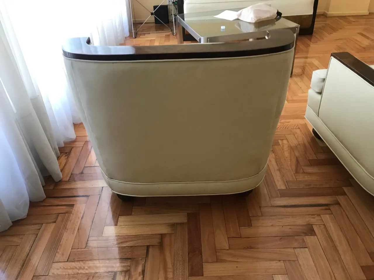 Vue arrière de 2 fauteuils anciens, montrant le détail du bois et le design classique, dans un cadre de salon accueillant.