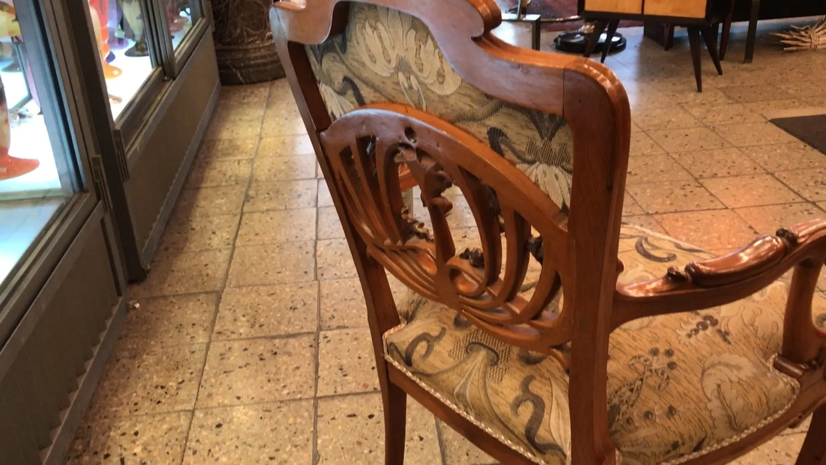 Tre poltrone antiche con braccioli intagliati e tessuto decorativo in un ambiente accogliente.