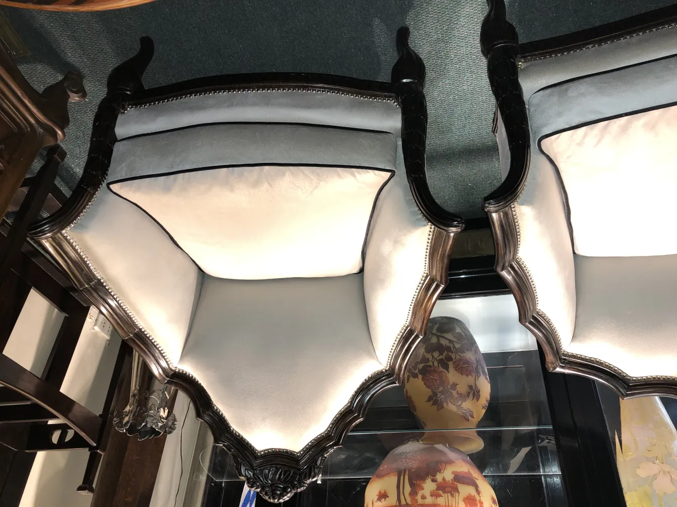 Três poltronas antigas com detalhes intrincados e almofadas espaçosas, em um ambiente elegante.