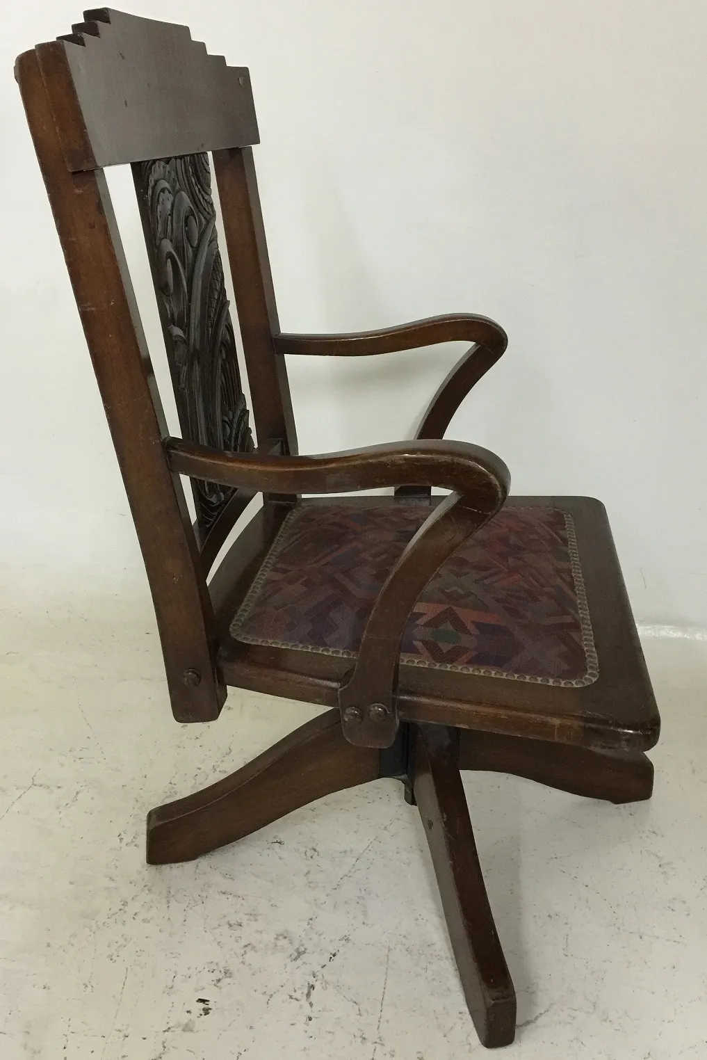 Antique desk chair with decorative design in a simple setting.