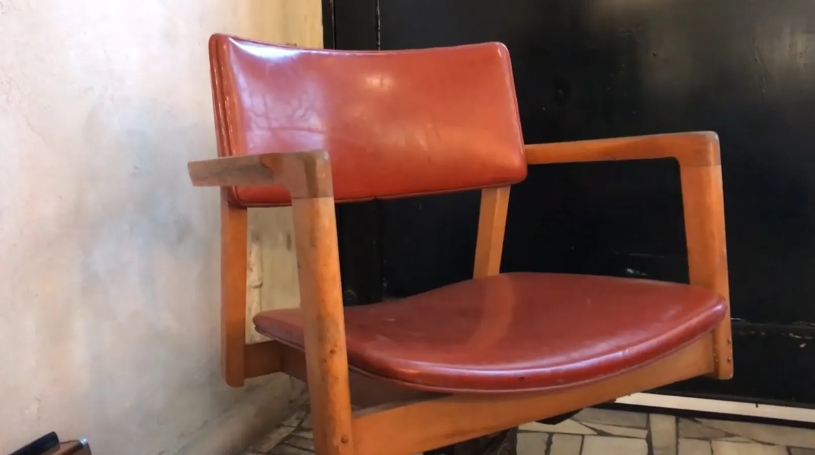 Antique desk chair with armrests and brown upholstery