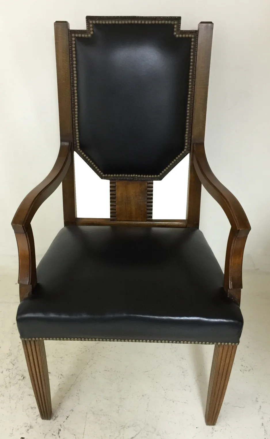 Sillón de escritorio antiguo con respaldo negro y detalles dorados, en un entorno sencillo.