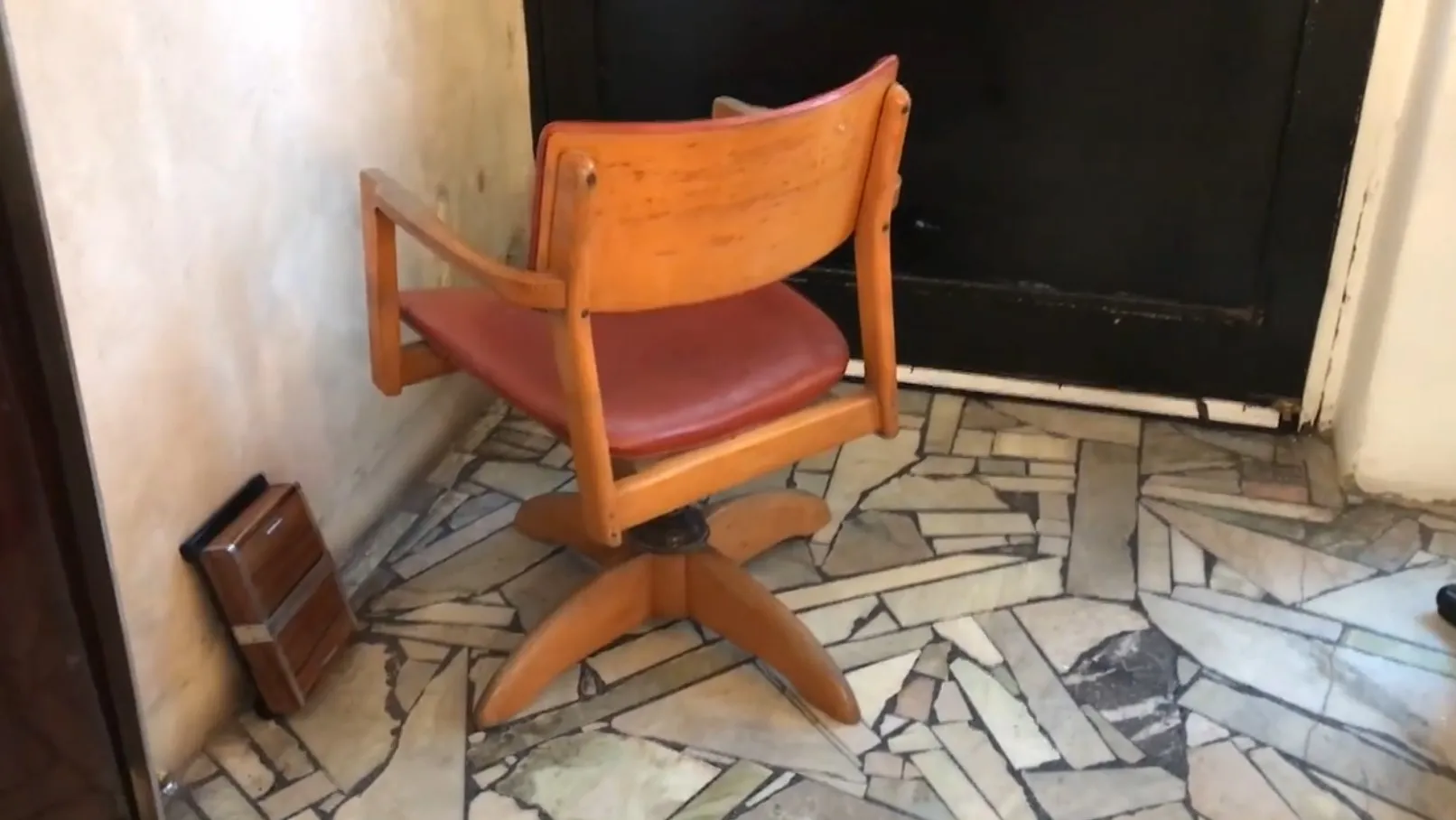 Antiker Bürosessel in einem Raum mit hellem Wand, warme Atmosphäre.