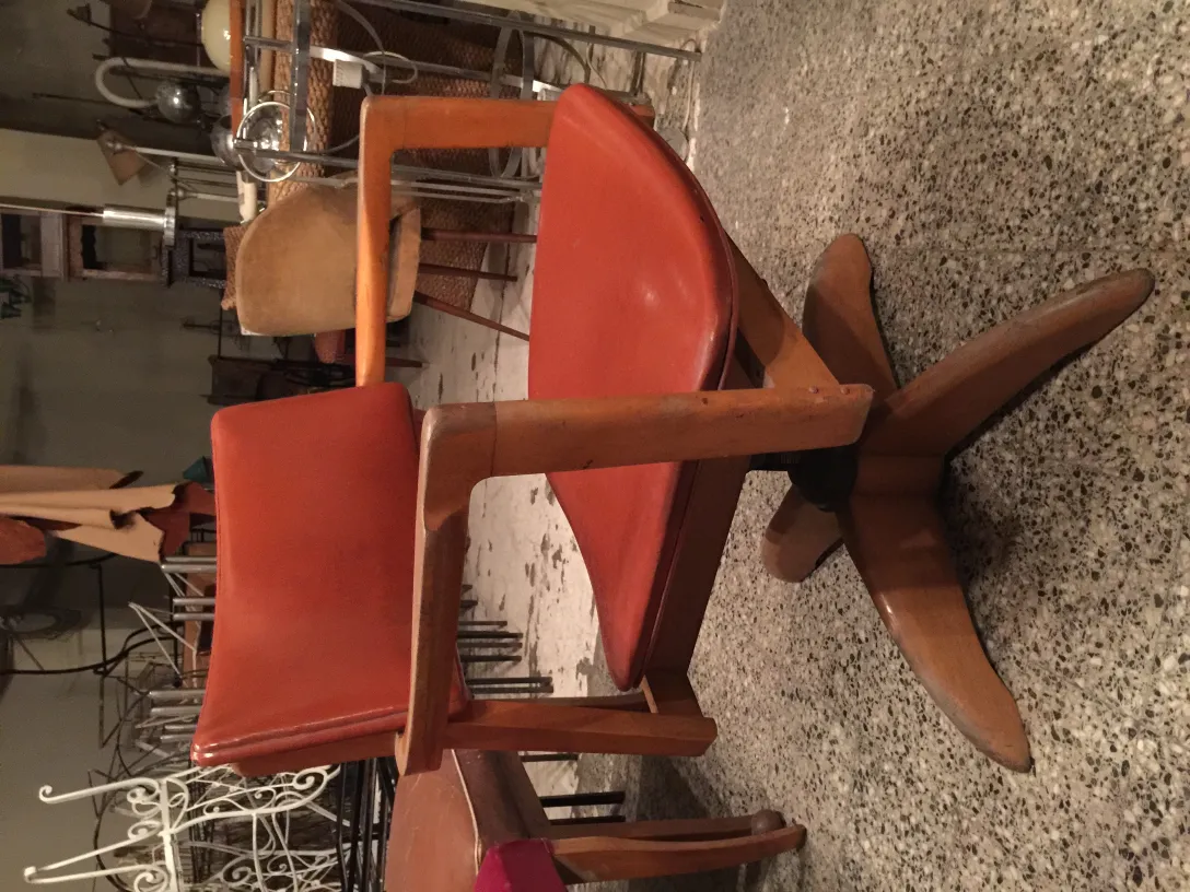 Sillón de escritorio antiguo con asiento de color naranja en un ambiente de antigüedades