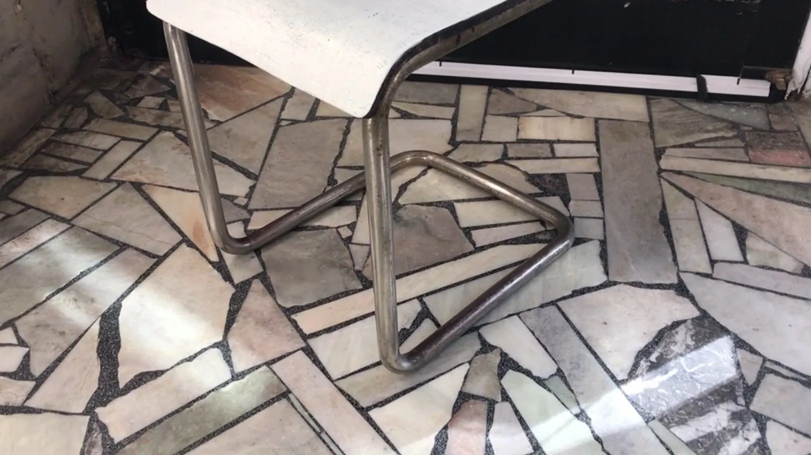 Fauteuil de bureau ancien avec base en métal dans un cadre neutre.