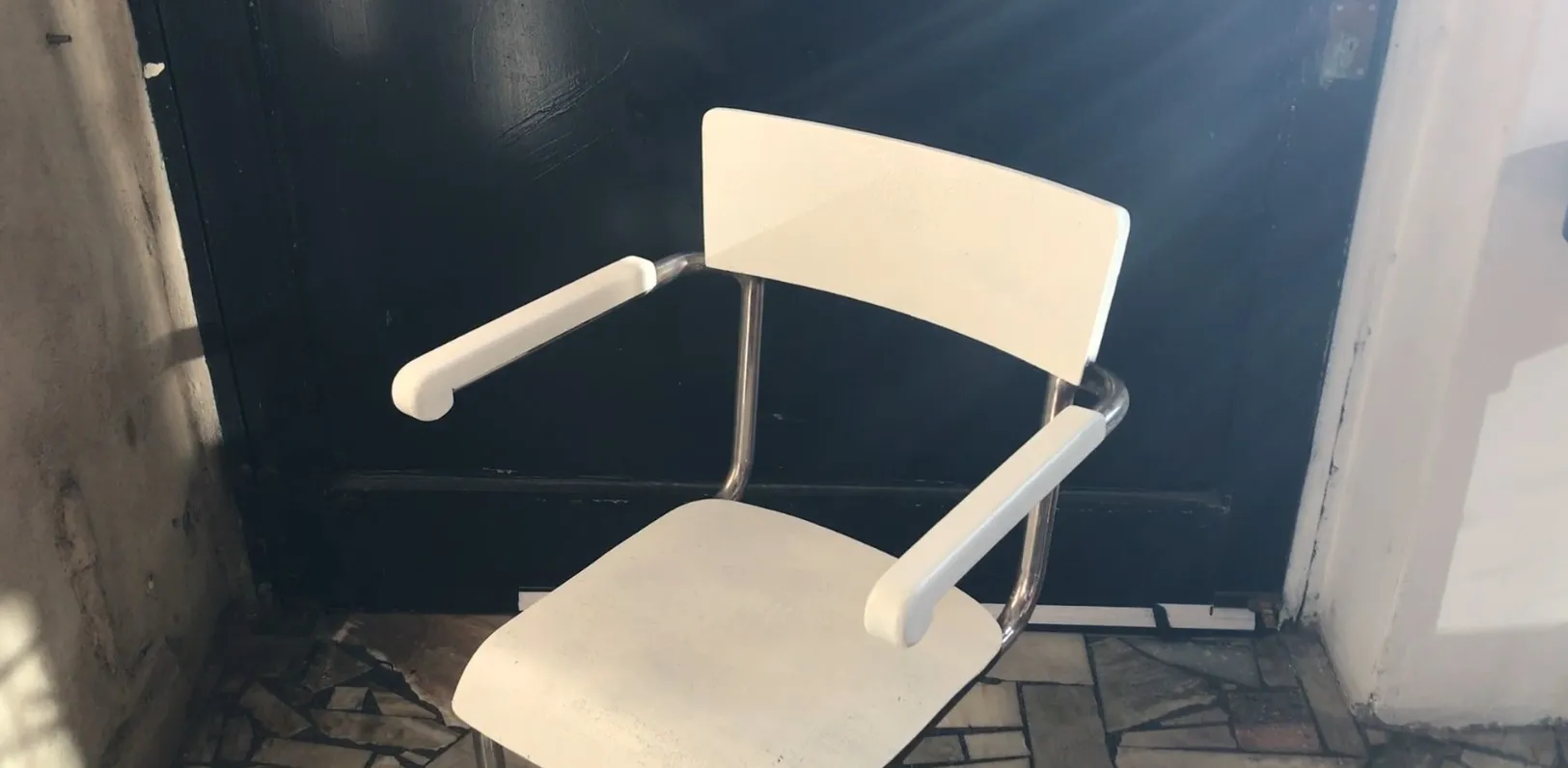 antique desk chair in white with arms, against a dark door