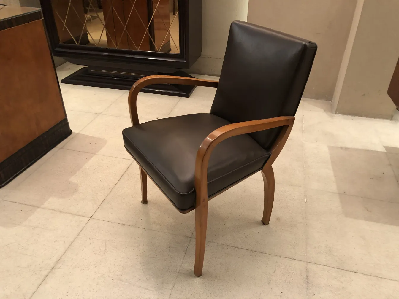 Antique desk chair in brown, featuring wooden arms, in a stylish setting.