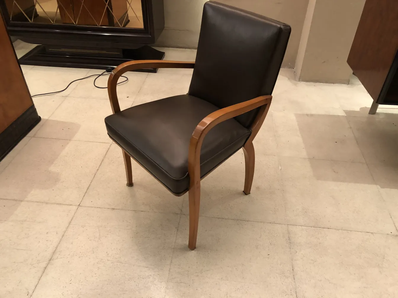 Sillón de escritorio antiguo con brazos de madera y tapizado en cuero oscuro, ambiente elegante.