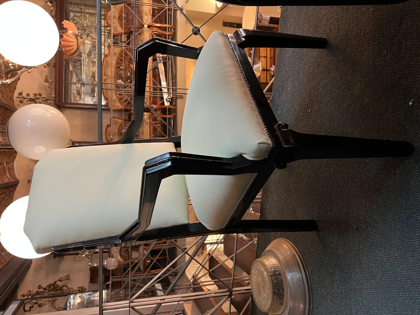 Antique desk chair with white seat and black arms in a classic environment.