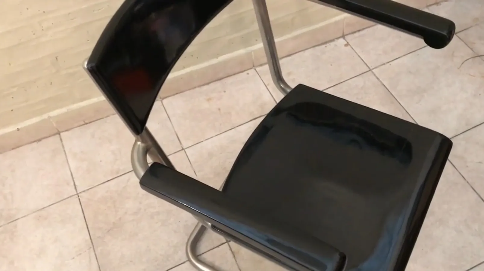 Cadeira de escritório antiga com braços, em um ambiente casual. Fundo claro.