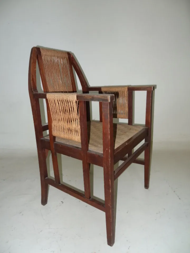 Fauteuil de bureau ancien avec détails aux bras et fond neutre.