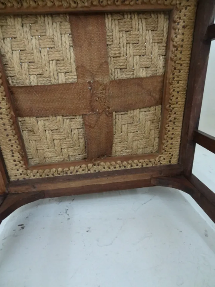 Vista detalle del sillon de escritorio antiguo con asiento tejido en una habitación clara.