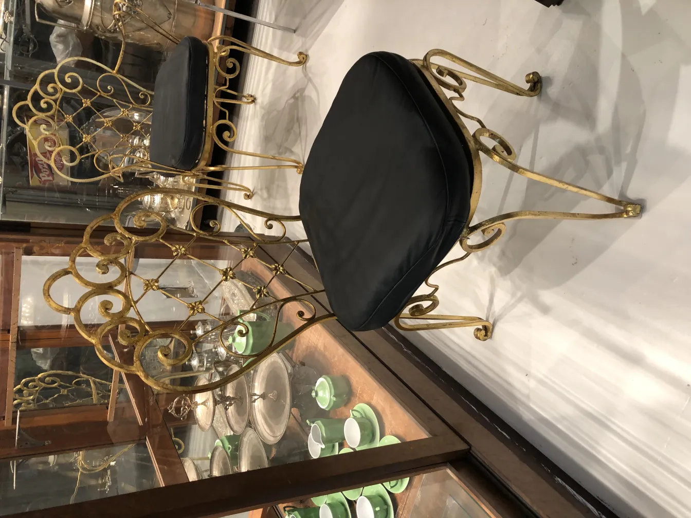 Zwei antike Stühle mit schwarzem Sitz und goldenem Design in einem dekorativen Umfeld.