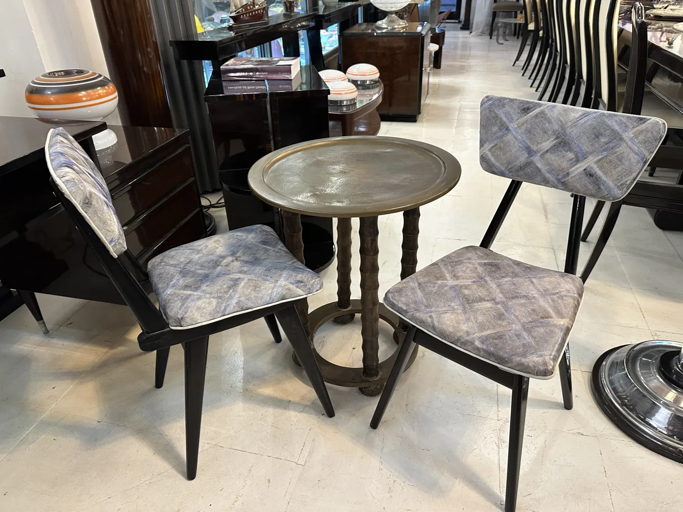 Two antique chairs with upholstery in a modern, elegant setting next to a round table
