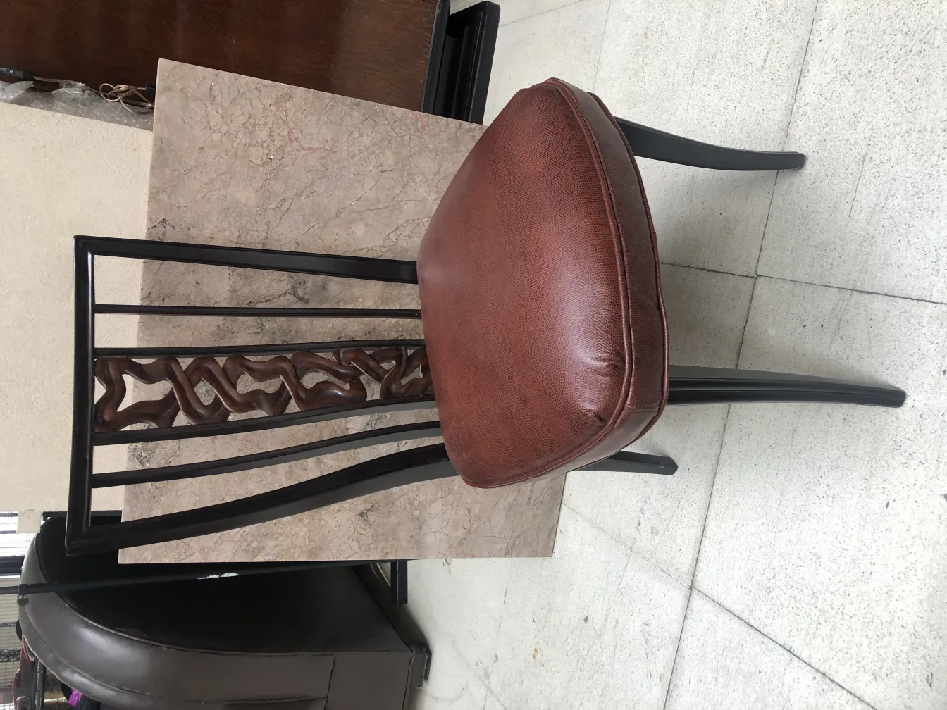 Vista de 2 cadeiras antigas com encosto decorativo em um ambiente neutro.