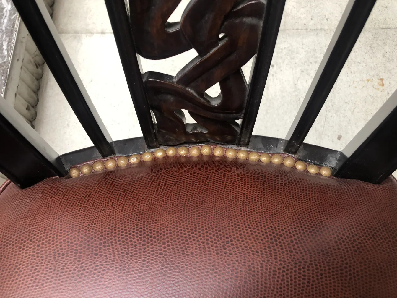 View of two antique chairs with decorative details on the backrest and cushion.