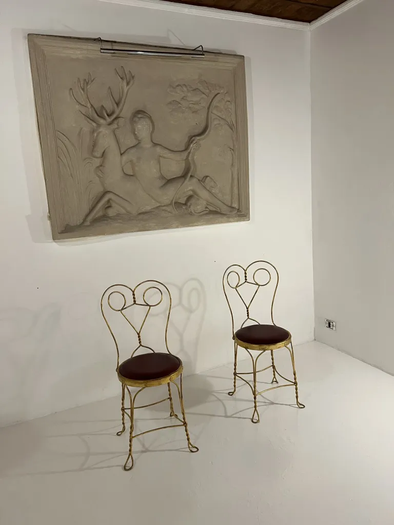 Duas cadeiras antigas com encostos decorativos em uma sala branca