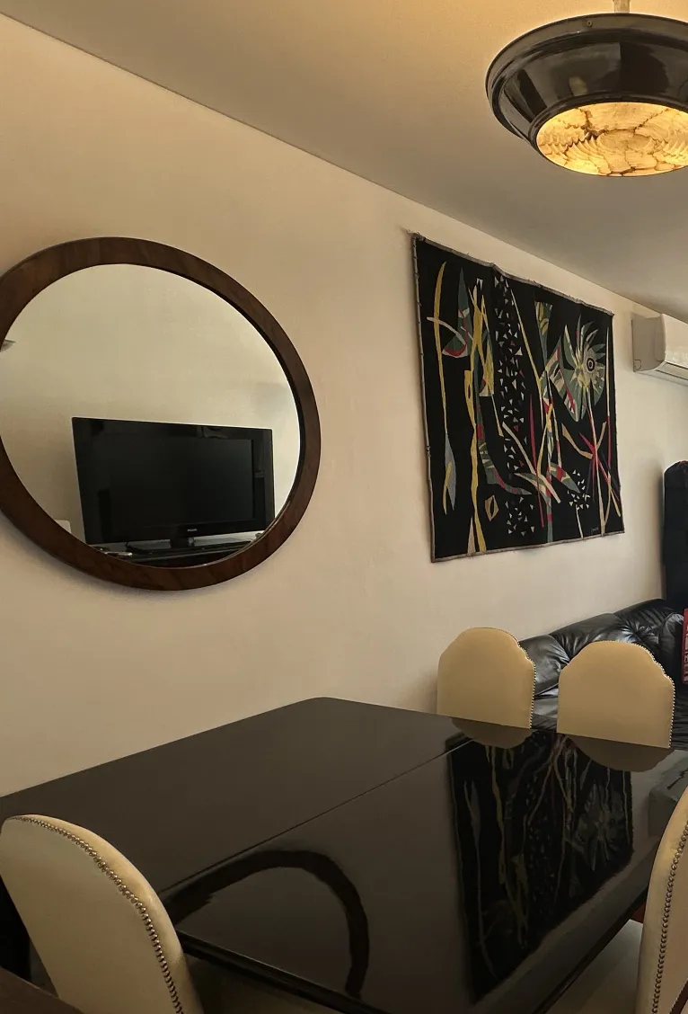 Sechs antike Esszimmerstühle in einem gemütlichen und eleganten Ambiente, mit einem runden Spiegel und einem bunten Kunstwerk an der Wand.