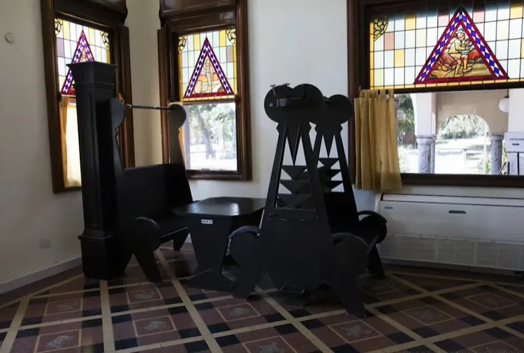 Six antique chairs in a room with stained glass