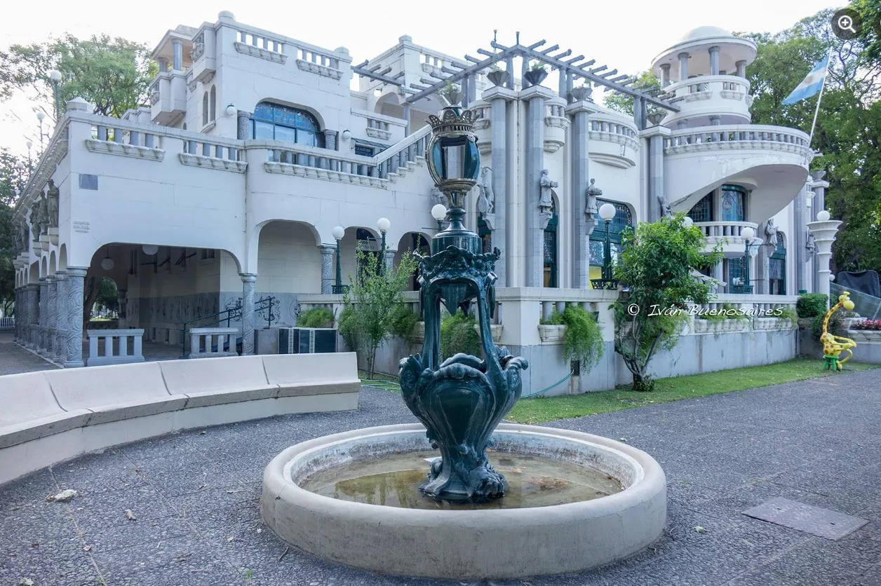 Sei sedie antiche disposte in uno spazio aperto, circondate da vegetazione e un edificio elegante.