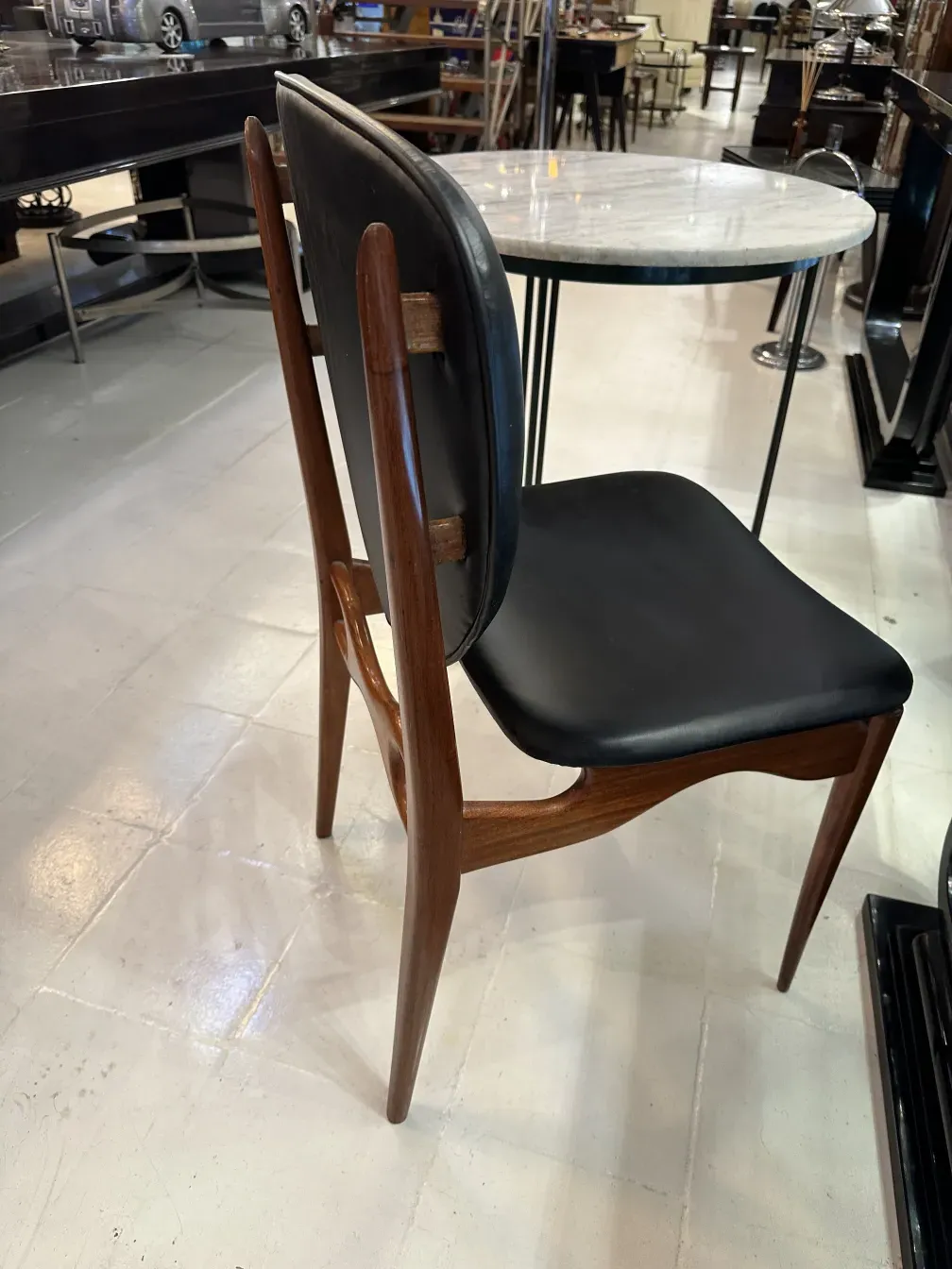 Side view of 8 antique finnjuhl chairs in a modern setting.