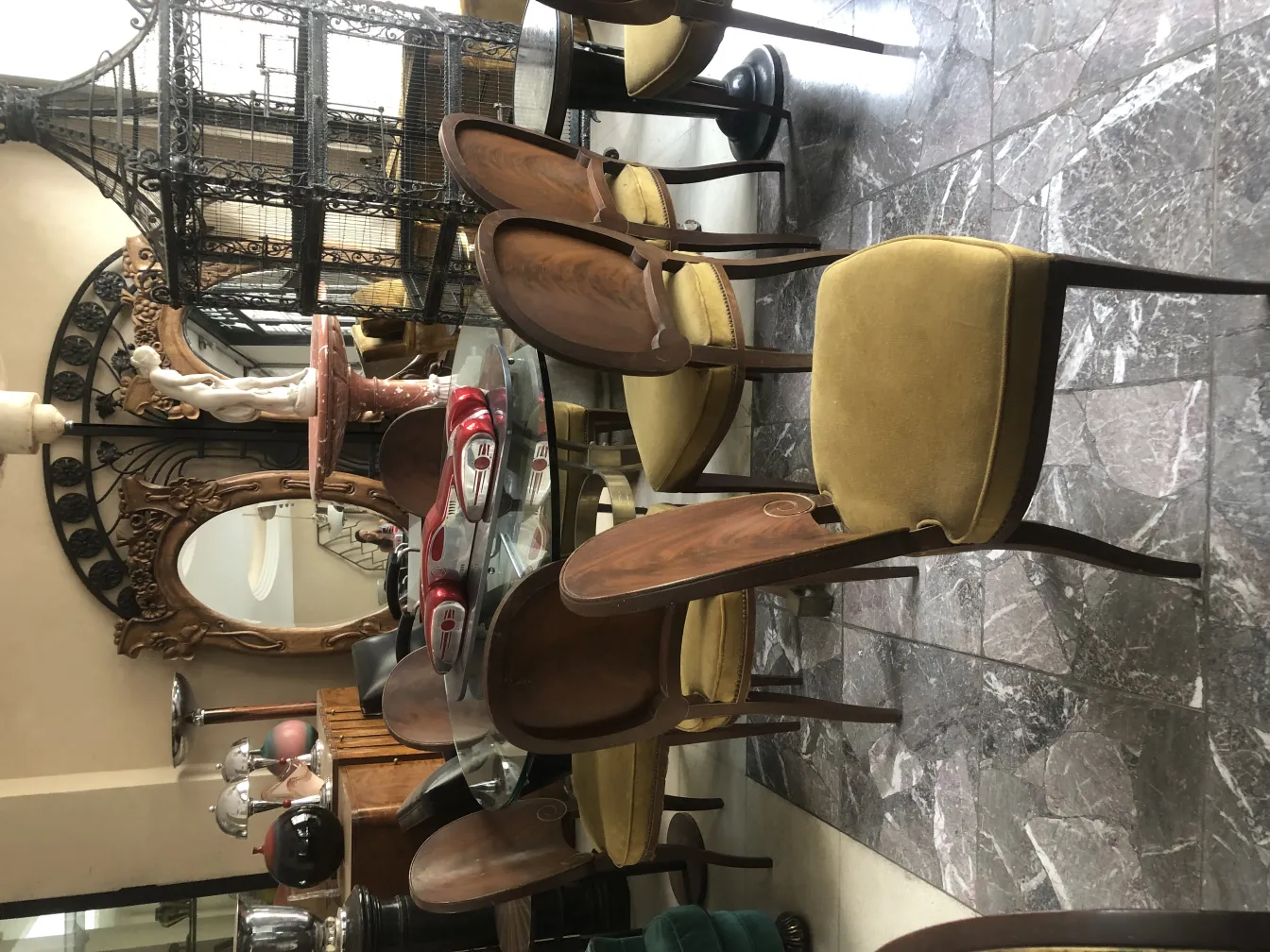 Huit chaises anciennes au design confortable, rembourrées d'une couleur jaune douce, se distinguent dans un cadre vintage.