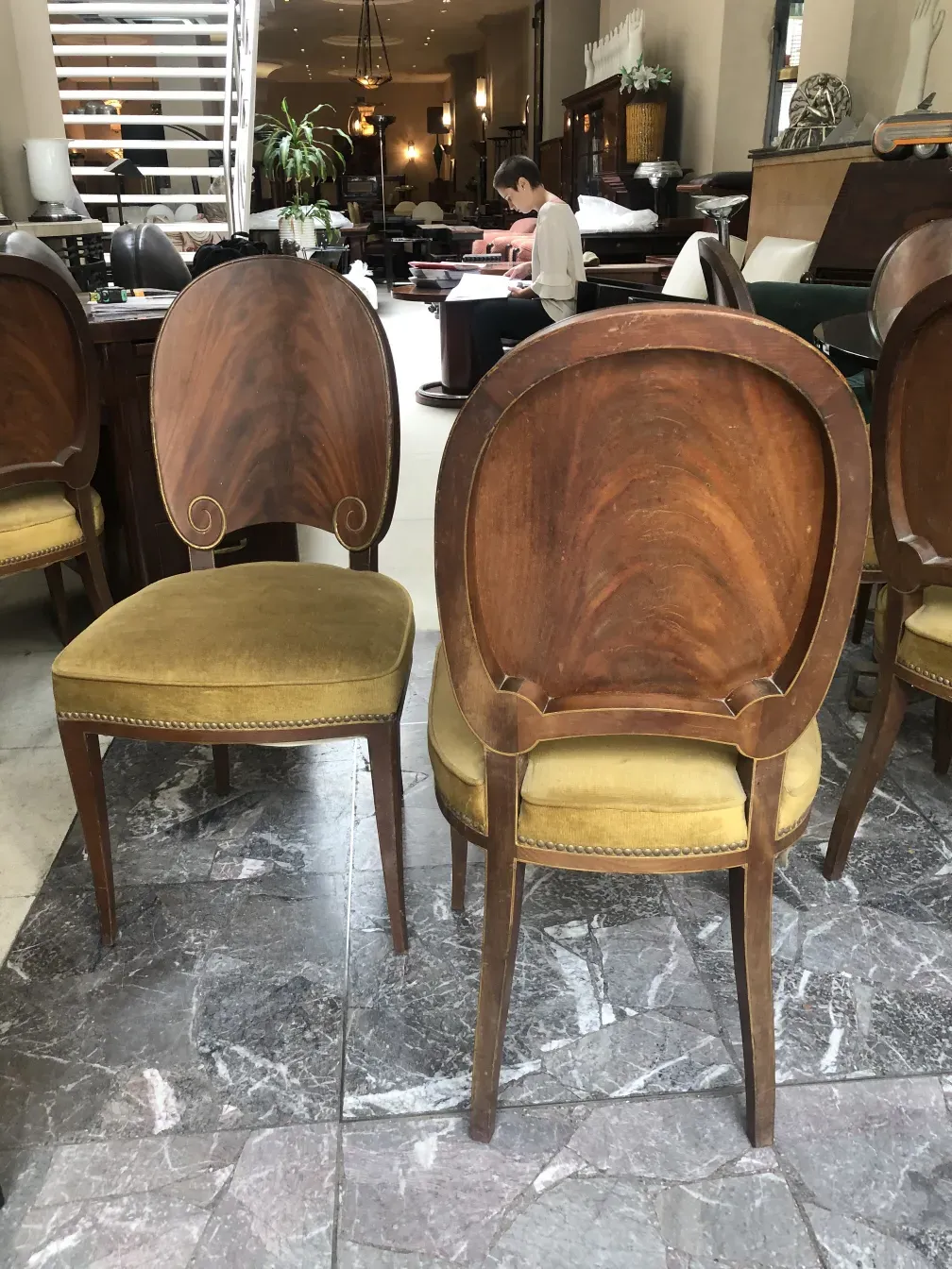 Vue de 12 chaises anciennes Jansen dans un magasin, montrant le dossier et le rembourrage vert.