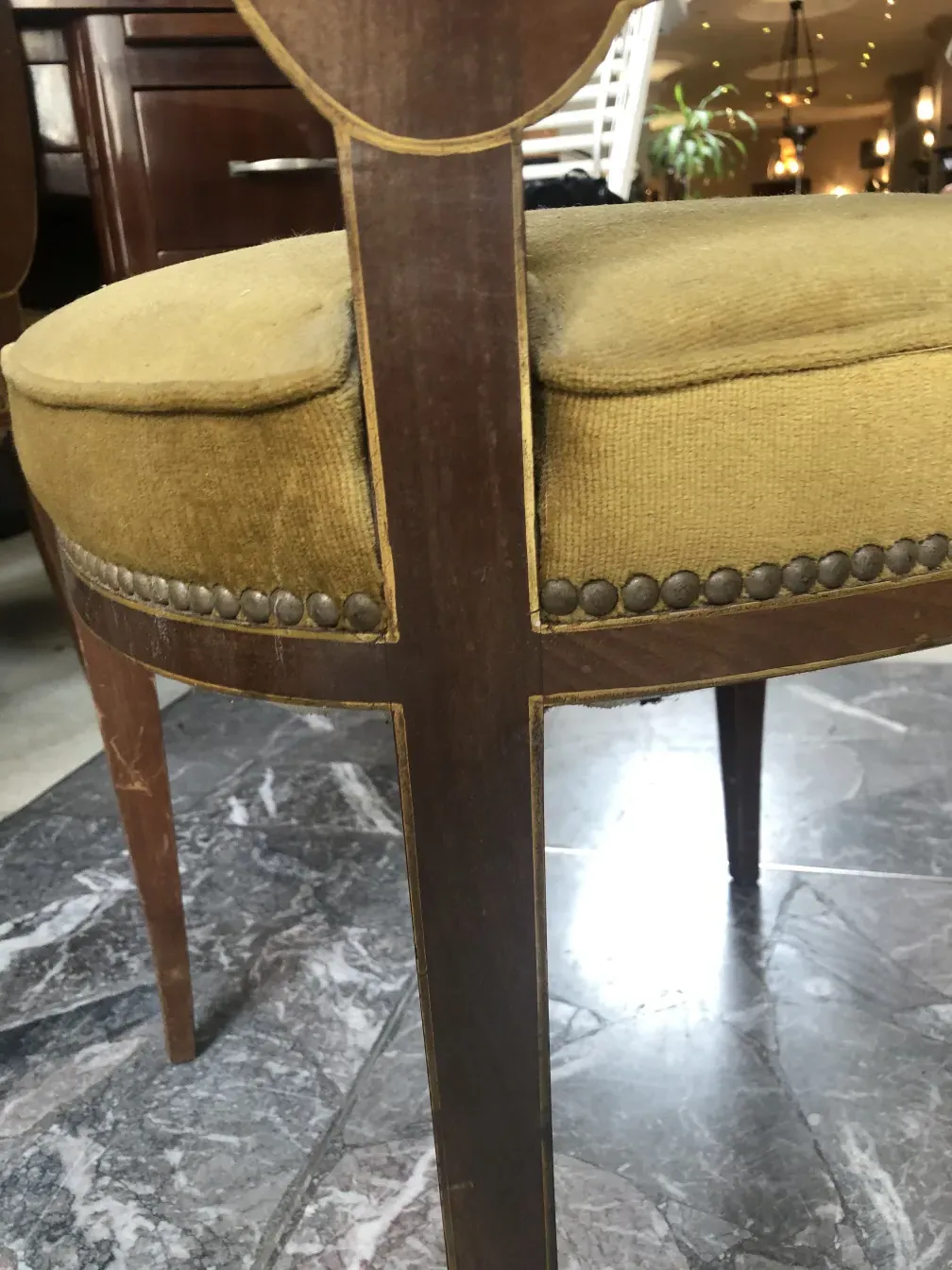Side view of an antique Jansen chair with yellow upholstery and decorative nails.