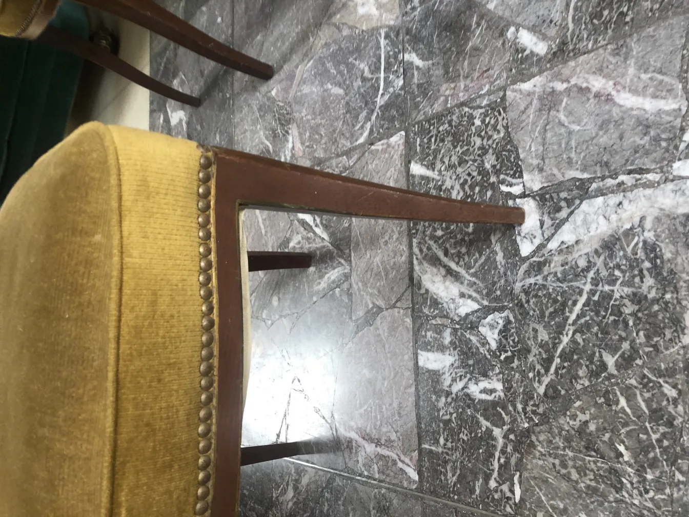 12 antike Stühle mit gelbem Polster und klassischem Design, auf einem Marmorboden.