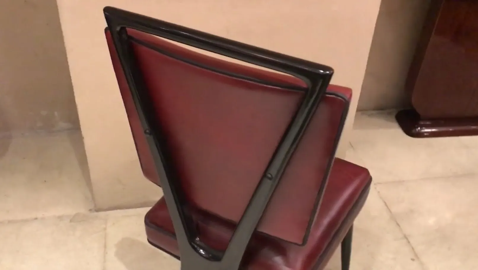 View of an antique chair with a red back and simple style