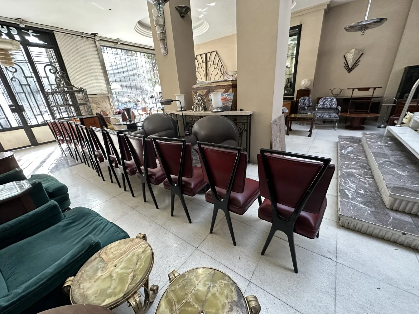 Un set di 12 sedie antiche con schienali triangolari e rivestimento rosso in un elegante ambiente antico.