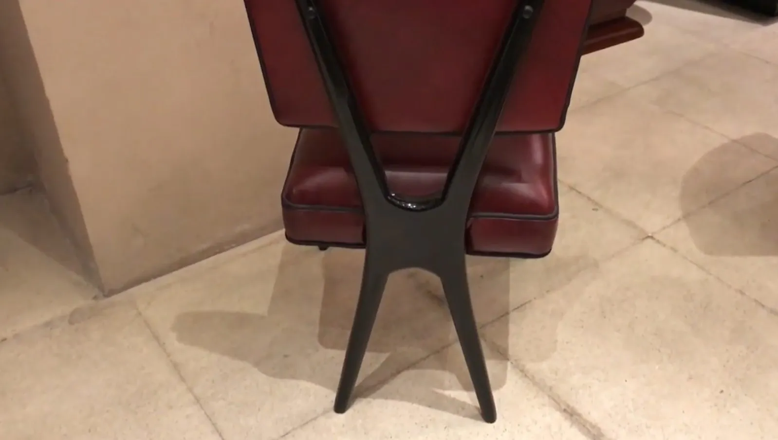 View of an antique chair design with X-shaped backrest and red padding.