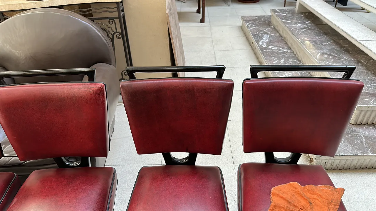 Ansicht von 12 roten antiken Stühlen in einer eleganten Umgebung mit einem zusätzlichen Stuhl im Hintergrund.