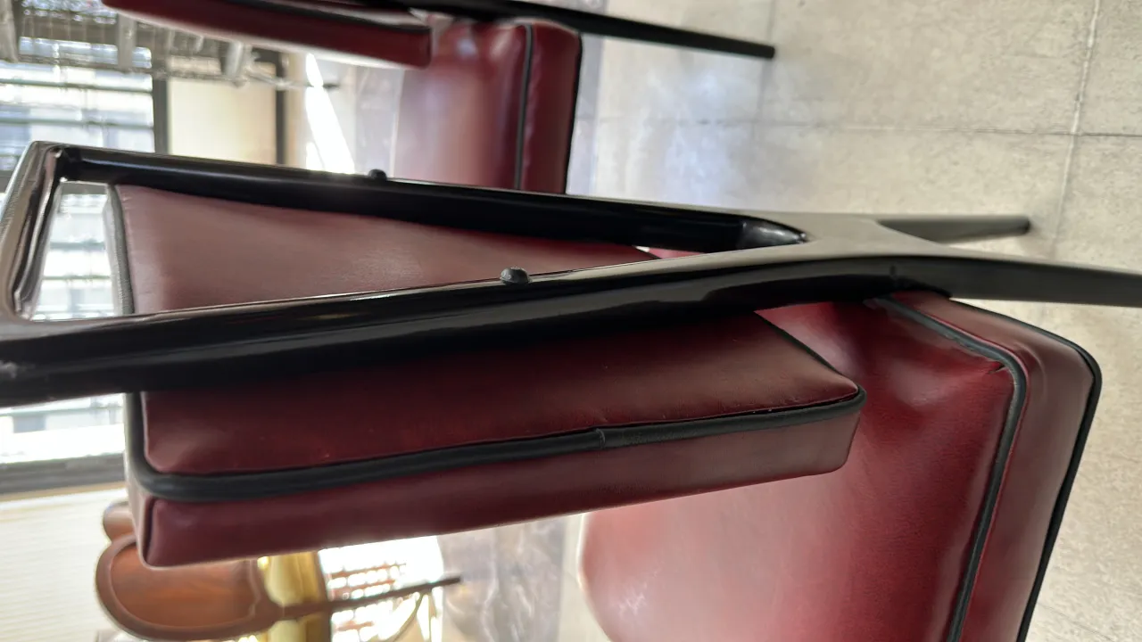 Вид 12 старинных стульев, сложенных, бордового цвета, в уютной обстановке.