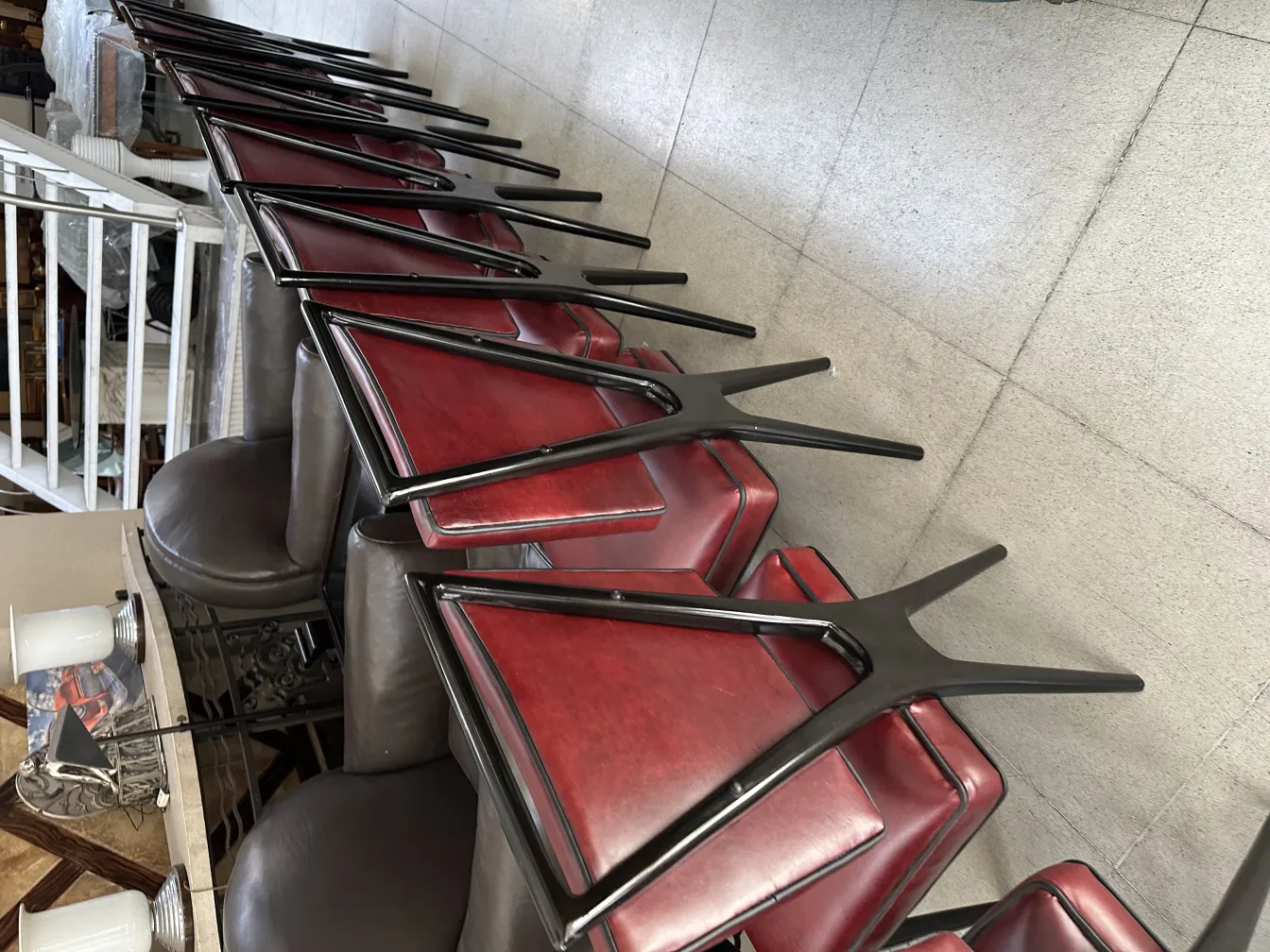 Dodici sedie antiche in stile classico con seduta rossa, disposte accanto a un tavolo.