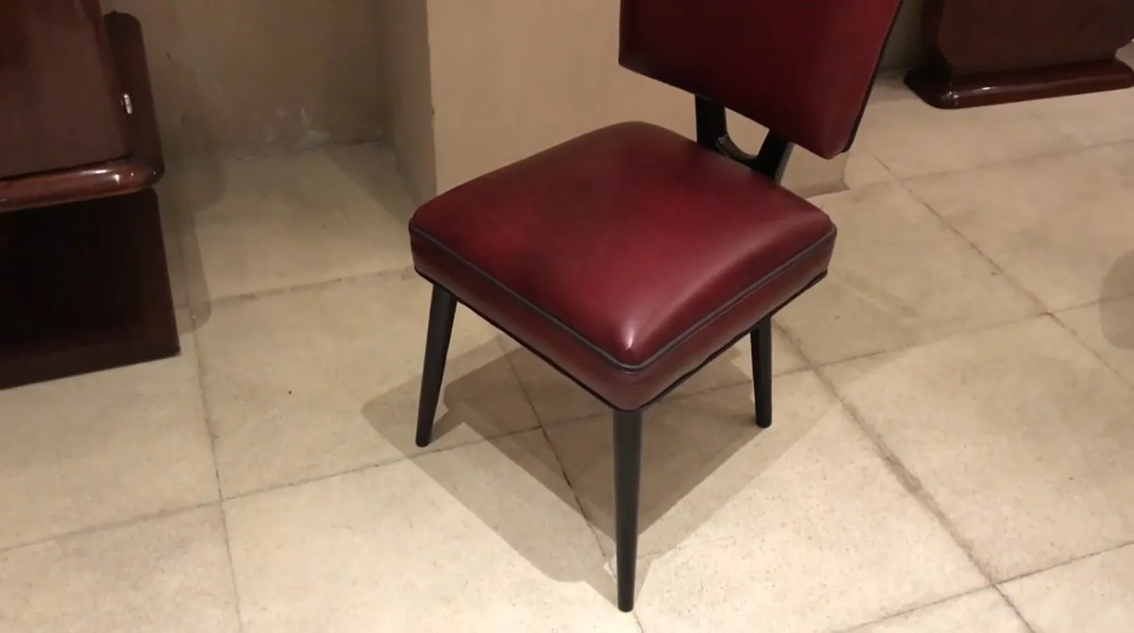 Cadeira antiga de cor bordô com pernas pretas