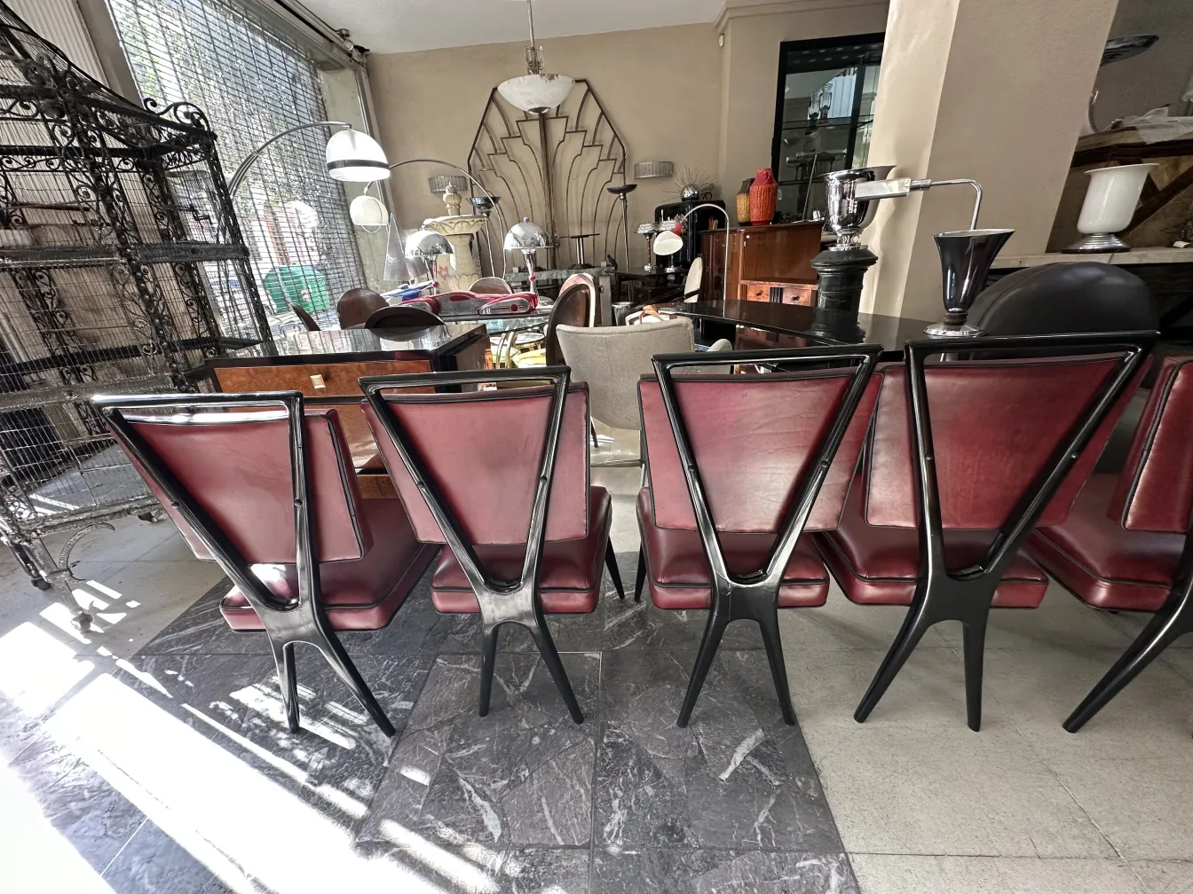 Vista de 12 sillas antiguas con patas estilizadas en un entorno moderno, rodeadas de iluminación elegante.