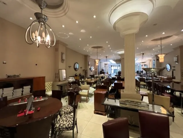 Vista de um restaurante com antigas 12 cadeiras e mesas elegantes.