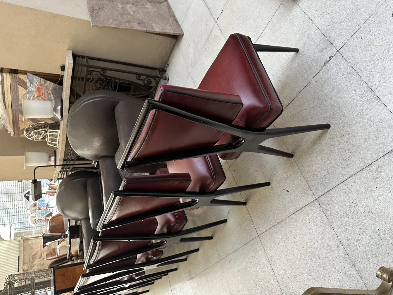 Zwölf gestapelte Stühle in Rot und Schwarz in einem antiken Ambiente.