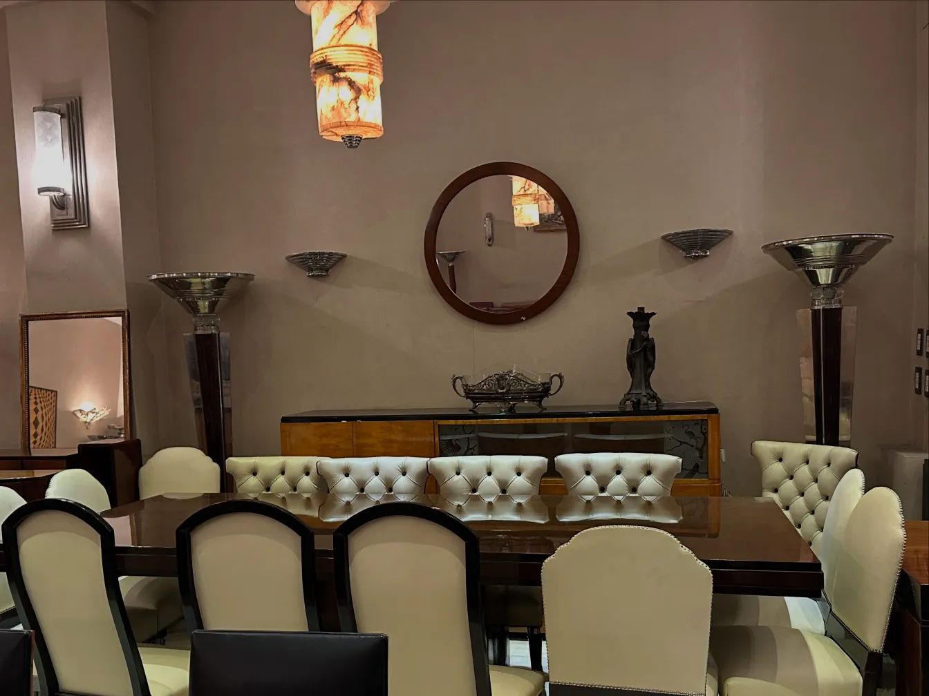 Vista de uma sala de jantar com 12 cadeiras antigas elegantes e uma lâmpada