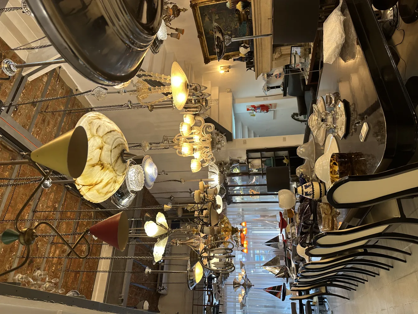 Vista de 12 sillas antiguas en un ambiente elegante, rodeadas de lámparas y decoración.