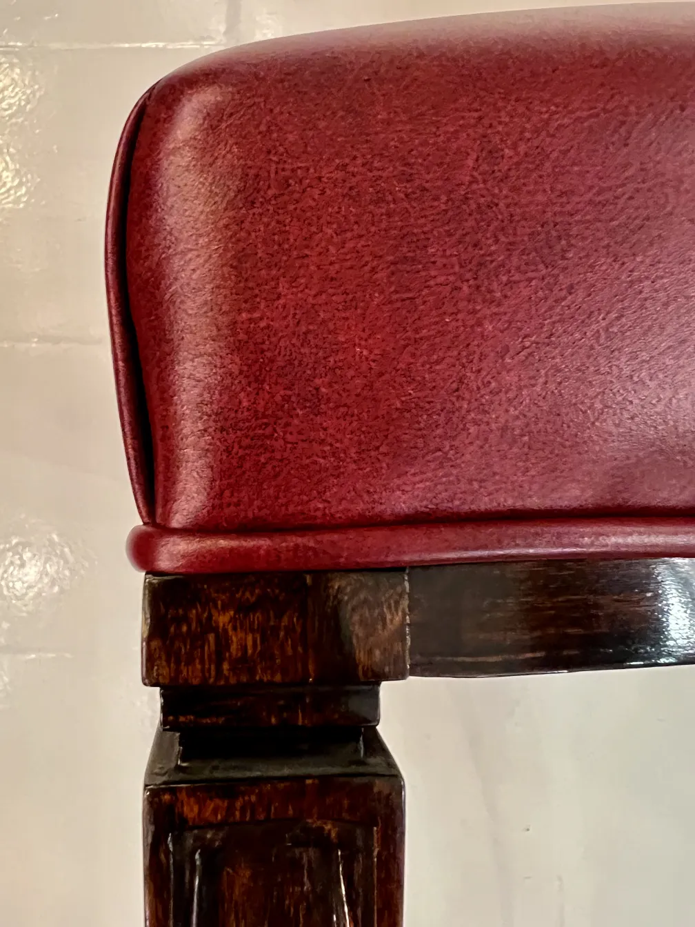 View of an antique chair with cushioned back, burgundy color.
